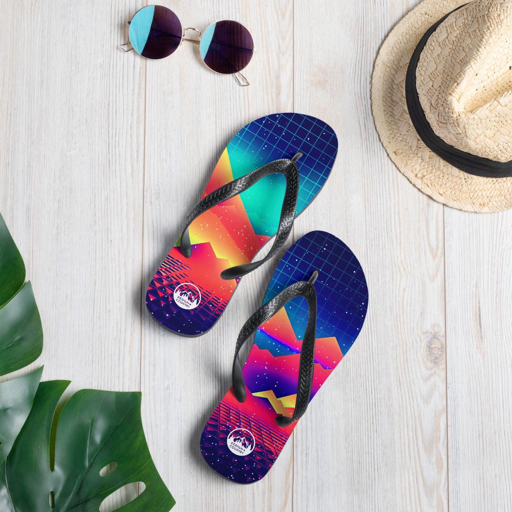 Colorful Techno - Synth Rave Flip-Flops with black rubber straps on wooden surface.