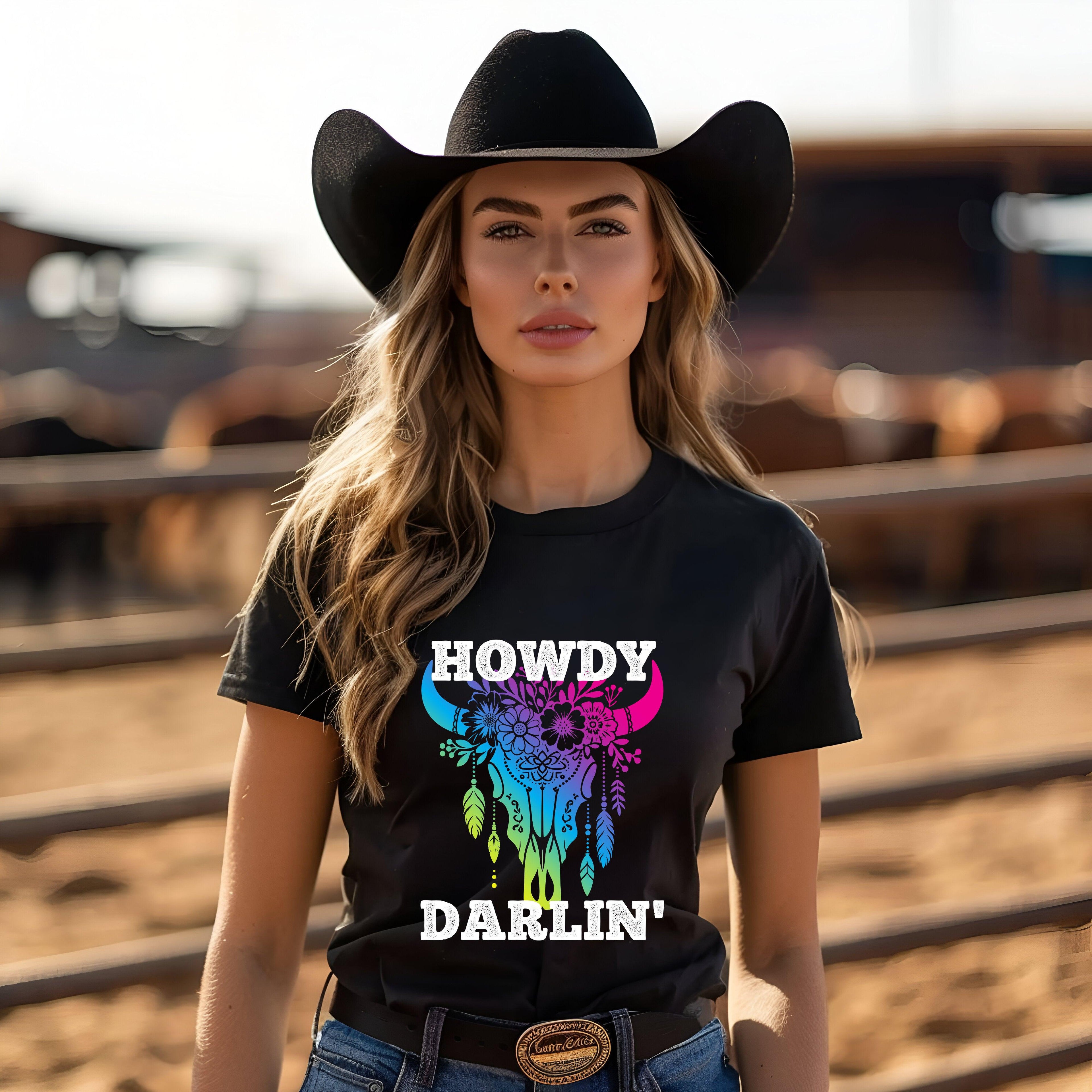 Cowgirl wearing black "Howdy Darlin' Cowboy Tee" with colorful design, perfect for rodeo style.